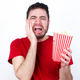 Young man in red T-shirt against white background eating popcorn, hiding face with hands pouting and crying, standing upset and depressed complaining about job problem.